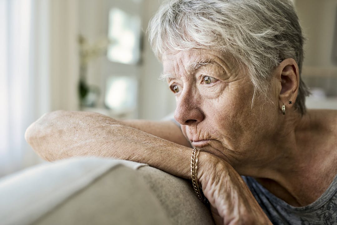 Portrait Of pensive Senior Woman On Sofa Suffering From Depression
