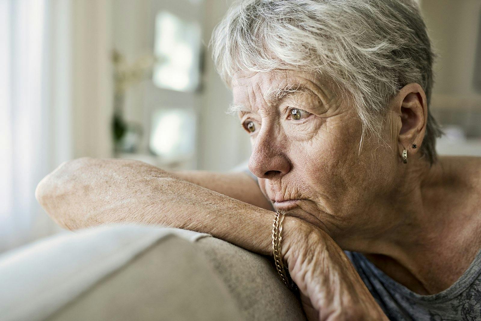 Portrait Of pensive Senior Woman On Sofa Suffering From Depression
