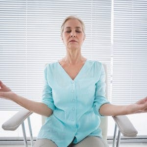 Senior woman doing yoga on chair at fitness studio
