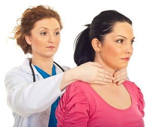 Doctor palpates patient&#8217;s neck to check thyroid gland
