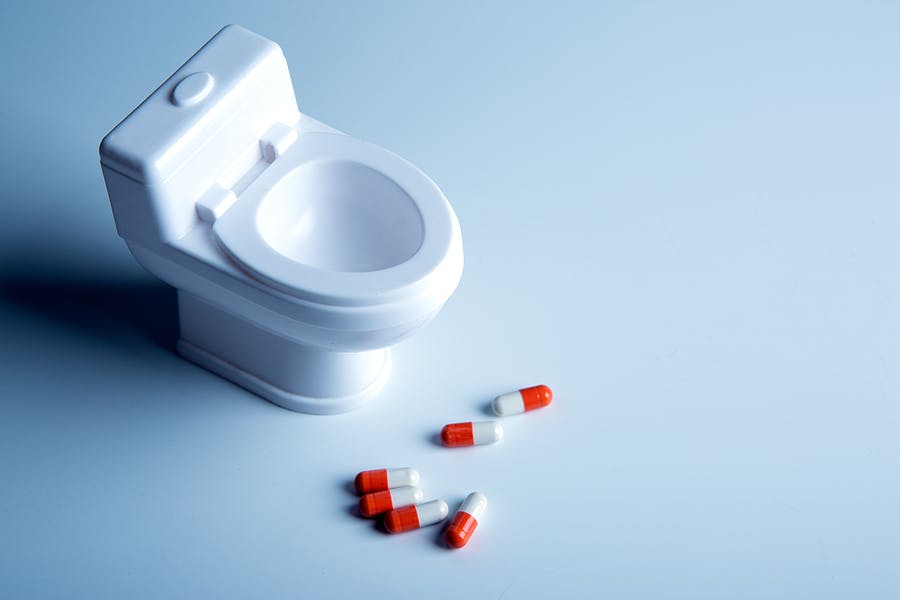 Toilet bowl miniature and pills on the table closeup
