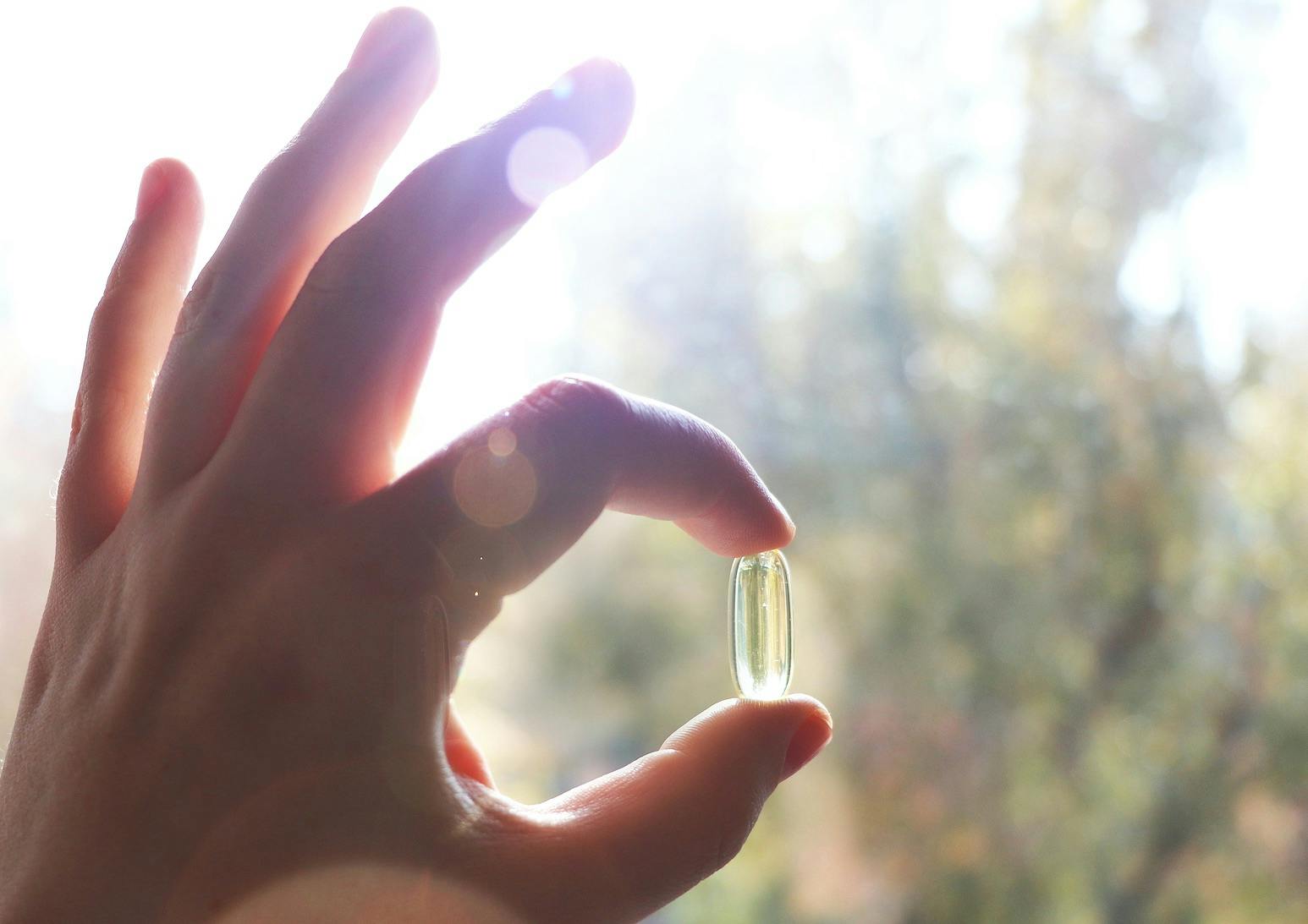 Vitamin D or omega 3 capsules. Vitamin gel in hand against the window. The concept of a lack of vitamin D in the body
