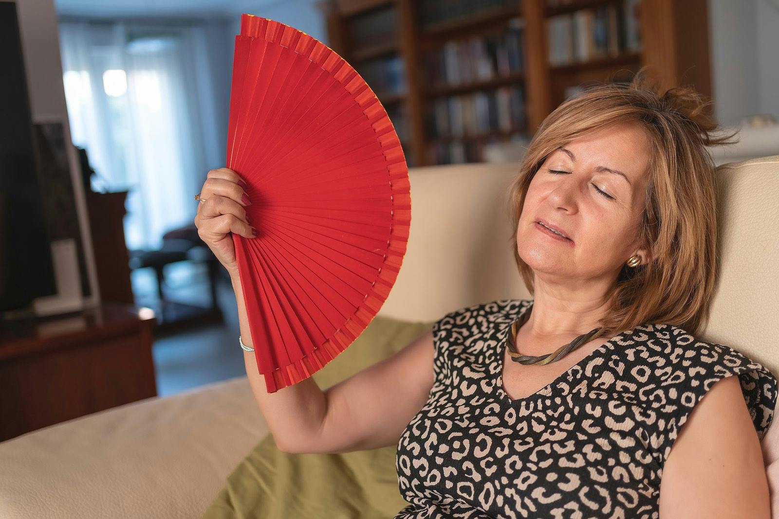 Adult woman fanned by the high heat produced by menopause and hormonal disorder.
