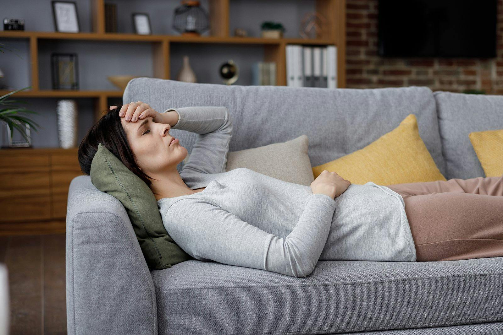 woman lying on a couch exhausted with long COVID