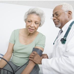 Male doctor &#038; female patient measuring her blood pressure
