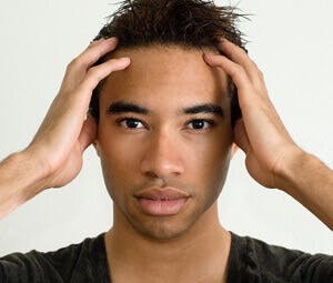 young man holds his hands to his head for dizziness or head pain