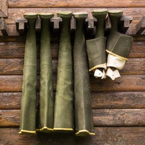 Hip waders hanging up to dry on outside of cabin wall
