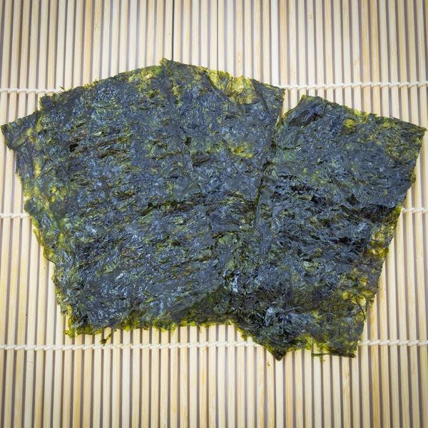Closeup roasted seaweed snack (kim nori) on traditional bamboo mat
