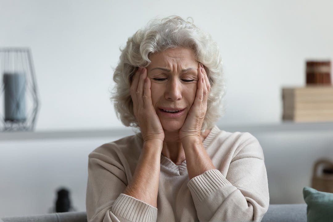 Upset exhausted mature 60s woman suffering from headache
