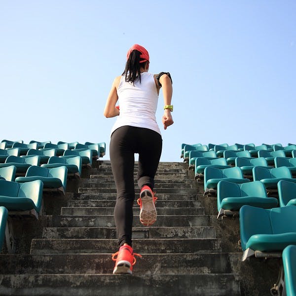 Woman running up a set of stadium stairs for exercise