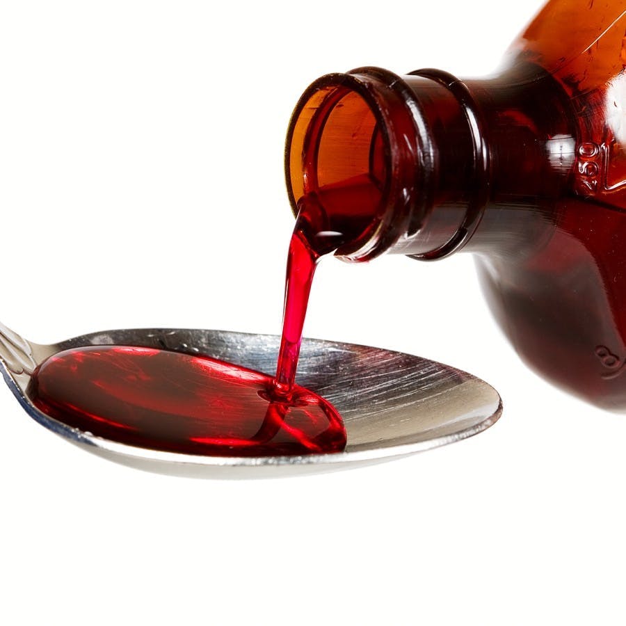 A bottle of cold medicine poured into a spoon
