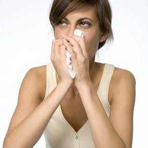 Young woman with runny nose and tissue
