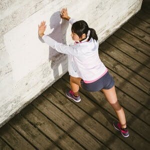 Beautiful asian female athlete stretching legs before running. Sporty young woman warming up for exercising and training outdoor.
