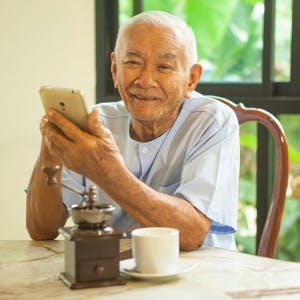 Happy asian senior man using the mobile phone in home
