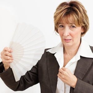 Hot flash flush, woman in suit fanning her face
