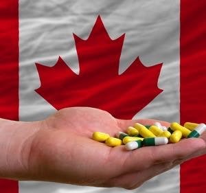 Man holding capsules in front of complete wavy national flag of canada symbolizing health medicine cure vitamines and healthy life
