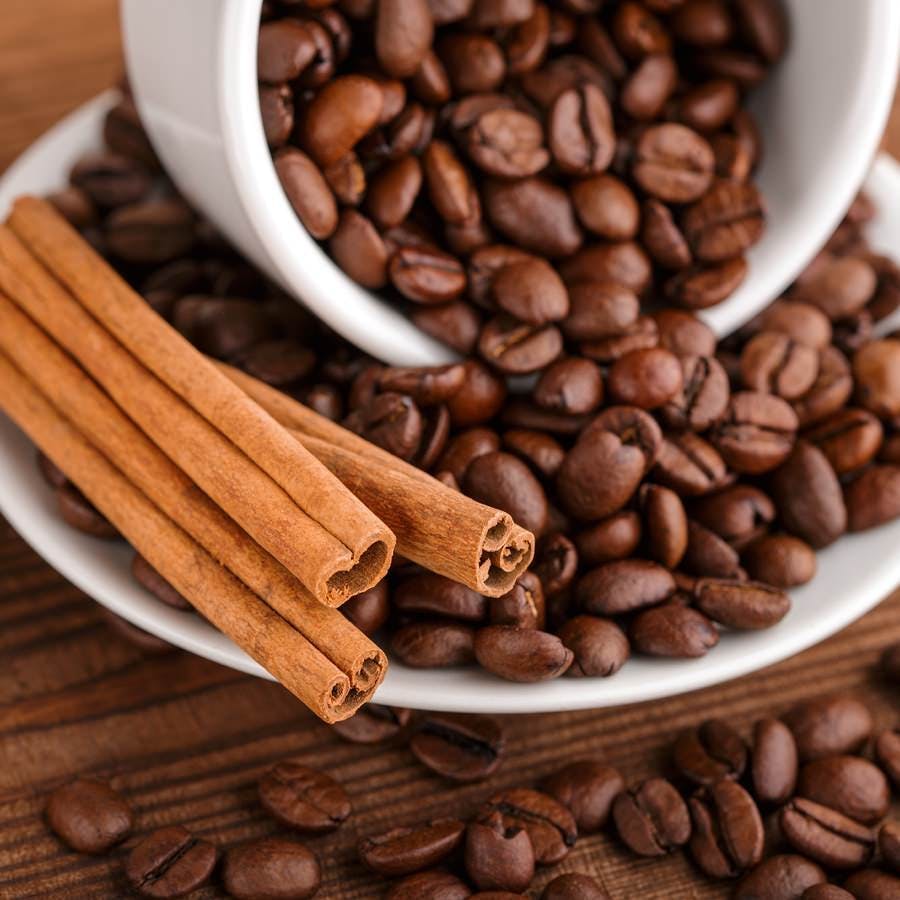 Coffee beans and cinnamon on a background of burlap. Roasted coffee beans background close up. Coffee beans pile from top with copy space for text. Seasoning. Spice. Cinnamon. Badian. Coffee house.
