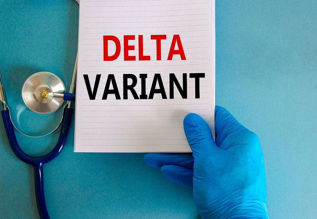 Covid-19 delta variant strain symbol. Doctor hand in blue glove with white card. Concept words &#8216;delta variant&#8217;. Stethoscope. Medical and COVID-19 delta variant strain concept. Copy space.
