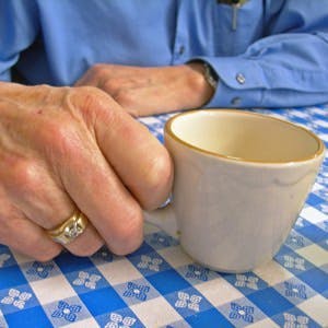 Elderly man holding coffee cup-close up shot.
