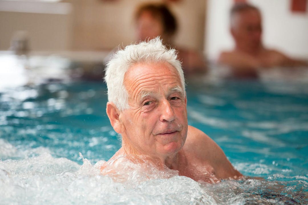 Elderly man enjoying in pool with hot water in spa resort

