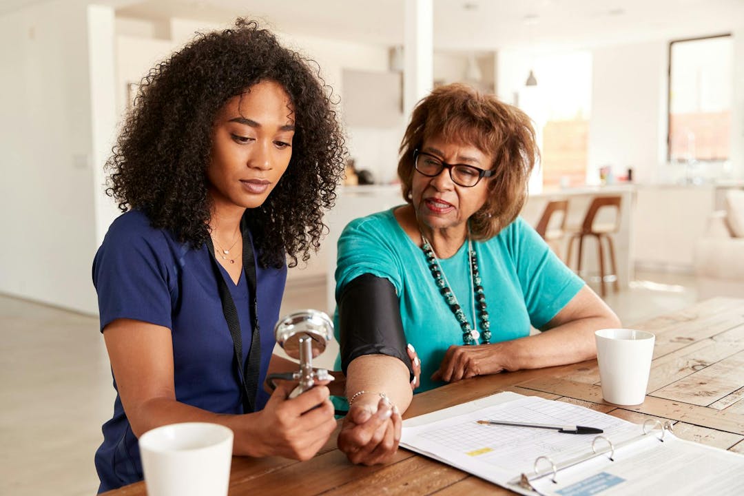 Female healthcare worker checking the blood pressure of a senior woman during a home visit
