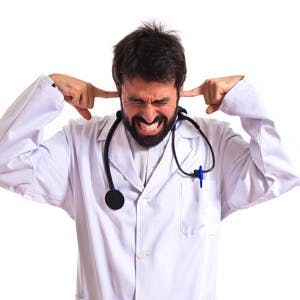 Doctor covering his ears over white background

