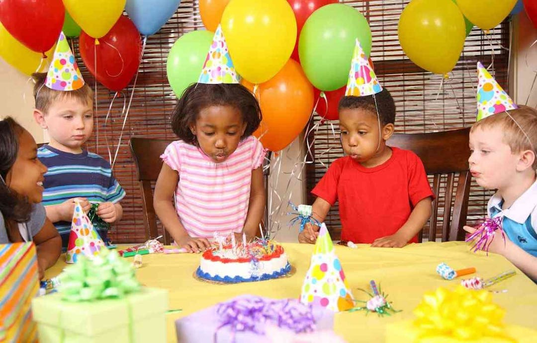 Young girl blowing out candles at birthday party
