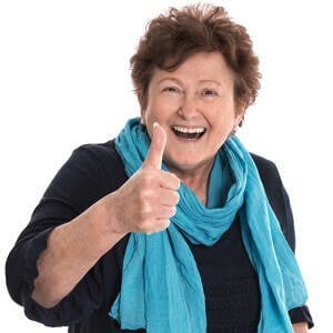 Happy isolated older lady wearing blue clothes with thumb up gesture over white background.
