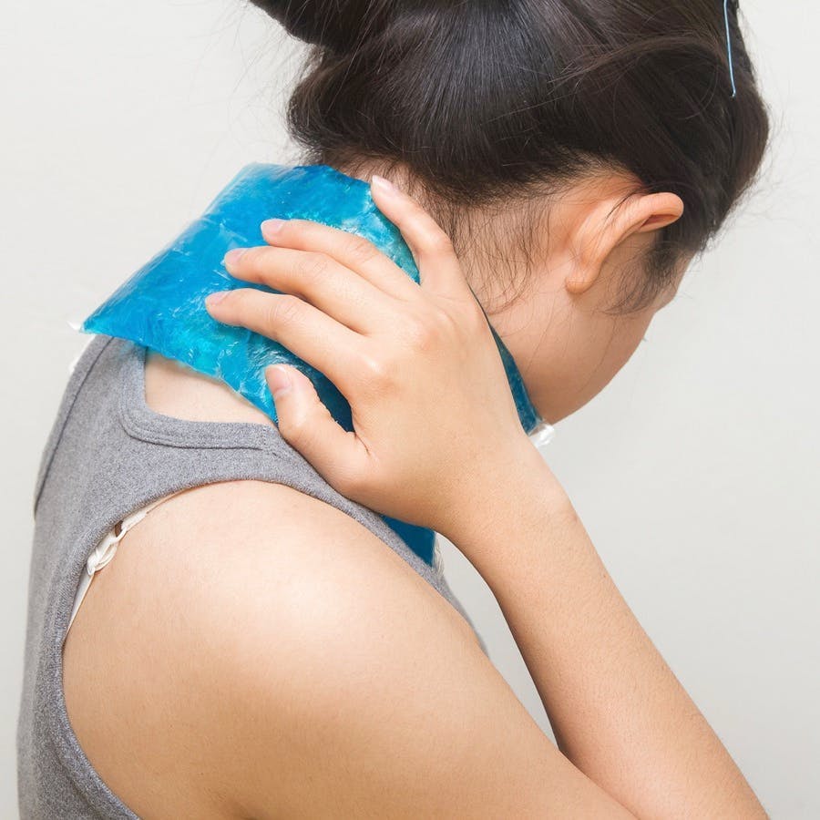 Woman putting gel pack on swollen neck
