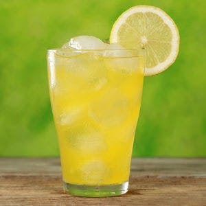 Cold orange lemonade in a glass with ice cubes, served with a slice of a lemon
