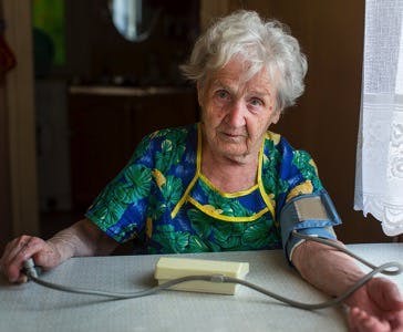 Elderly woman pensioner measures the blood pressure itself.

