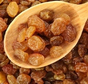 Raisins in wooden spoon on raisins background
