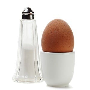 Boiled brown egg in eggcup with salt shaker isolated on white background
