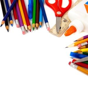 Assorted school supplies including pens pencils scissors glue and a ruler on a white background
