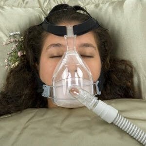 Anti-snoring device, sleeping woman with CPAP machine on nose and mouth
