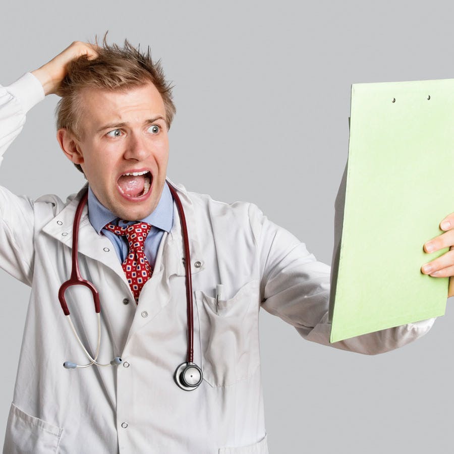 Male doctor terrified looking at medical reports over gray background
