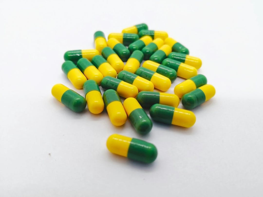 Medication concept. Many yellow-green capsules of Tramadol 50 mg. isolated on white background, narcotic- like pain reliever, used to treat moderate to severe pain. Selective focus and copy space.
