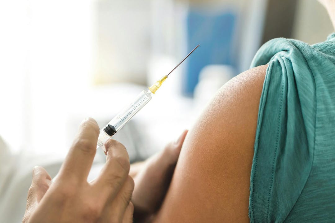 Vaccine or flu shot in injection needle. Doctor working with patient&#8217;s arm. Physician or nurse giving vaccination and immunity to virus, influenza or HPV with syringe. Appointment with medical expert.
