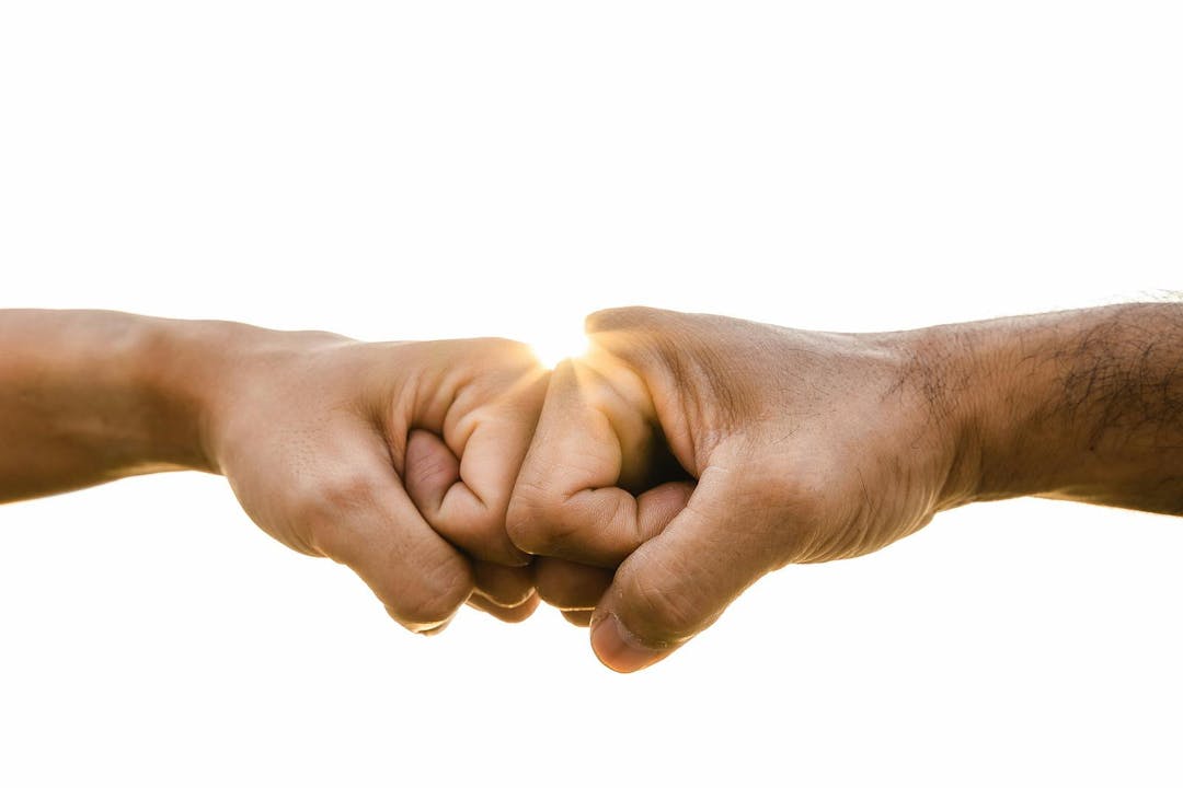Closeup young man fist bump on the sky background. Friendship & Teamwork Concept.

