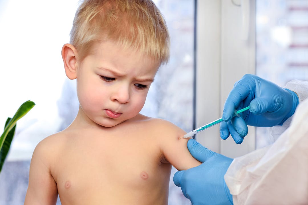 Doctor injecting vaccination in arm of a little boy. Coronavirus vaccination. Doctor vaccinating child. Little boy getting flu shot. Pediatrician giving injection. Concept of children&#8217;s health.
