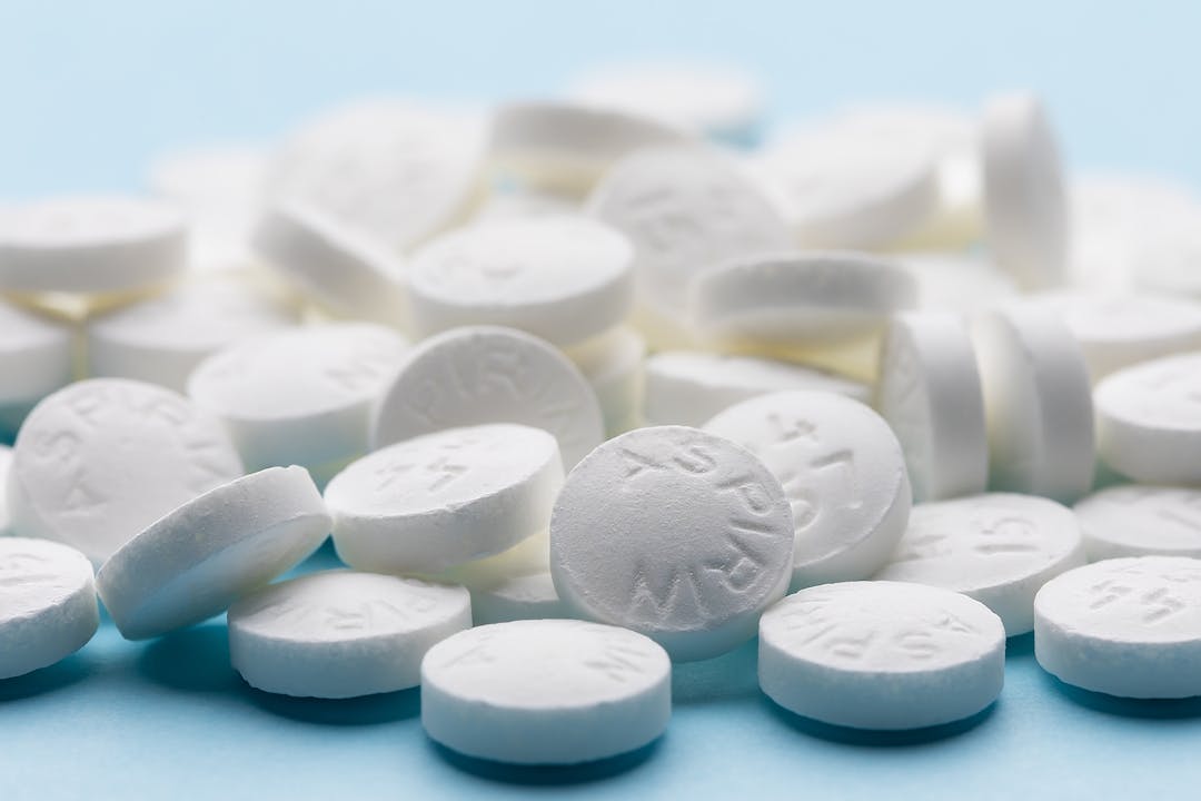 White aspirin pills on blue paper background. Pile of aspirin. Medical background
