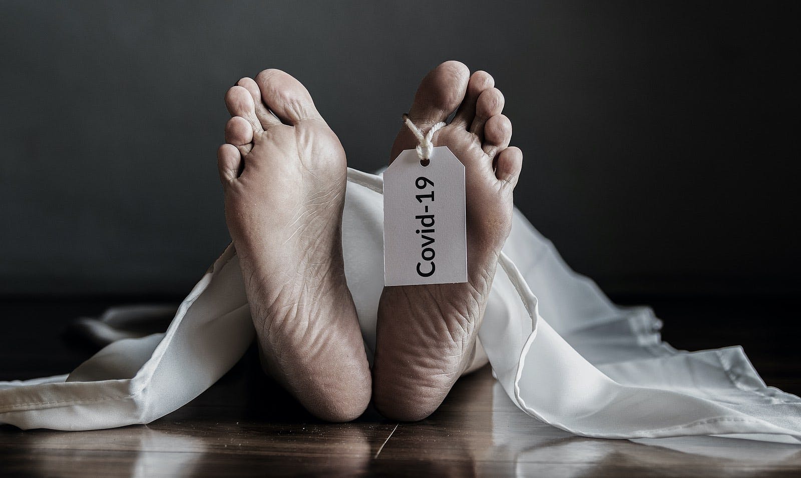 Dead body in morgue with a hanging COVID 19 tag hanging from toe