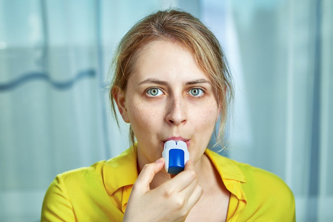 COPD or chronic obstructive pulmonary disease treatment with bronchodilator powder inhaler. A young woman uses dispenser with powders inhalation to relieve symptoms of asthma, and breathing relief.
